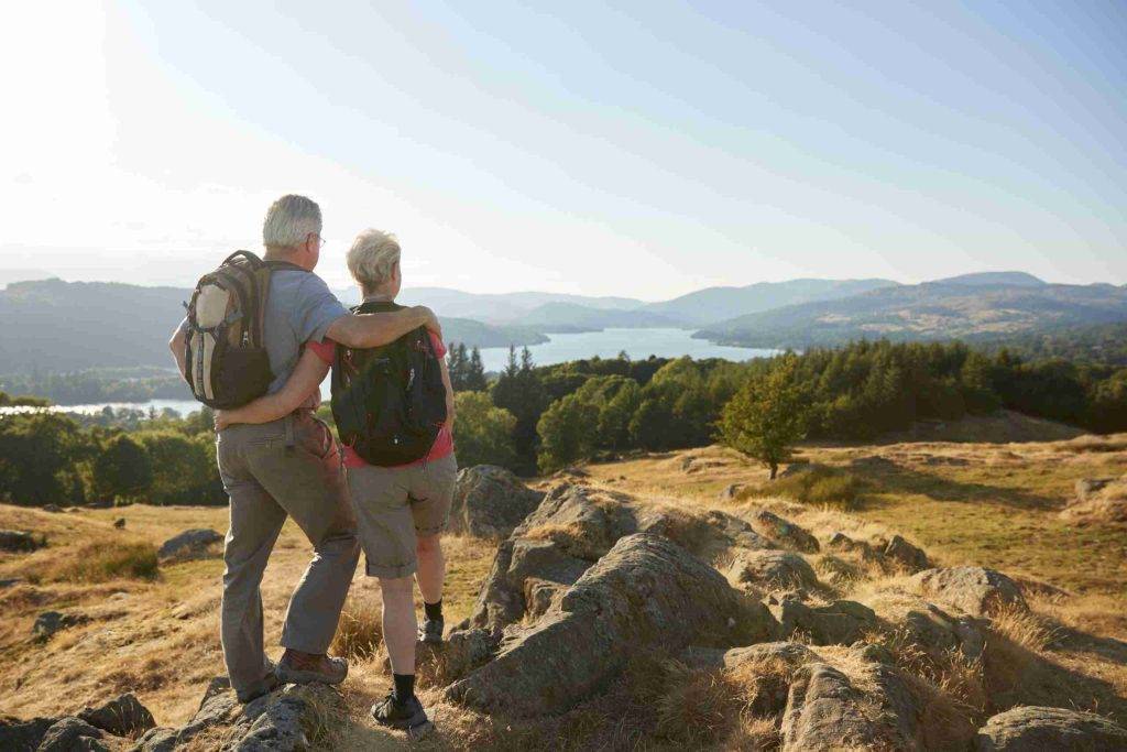 Goldstone Financial Hero - Rear View Of Senior Couple Standing At Top Of Hill On Hike Through Countryside