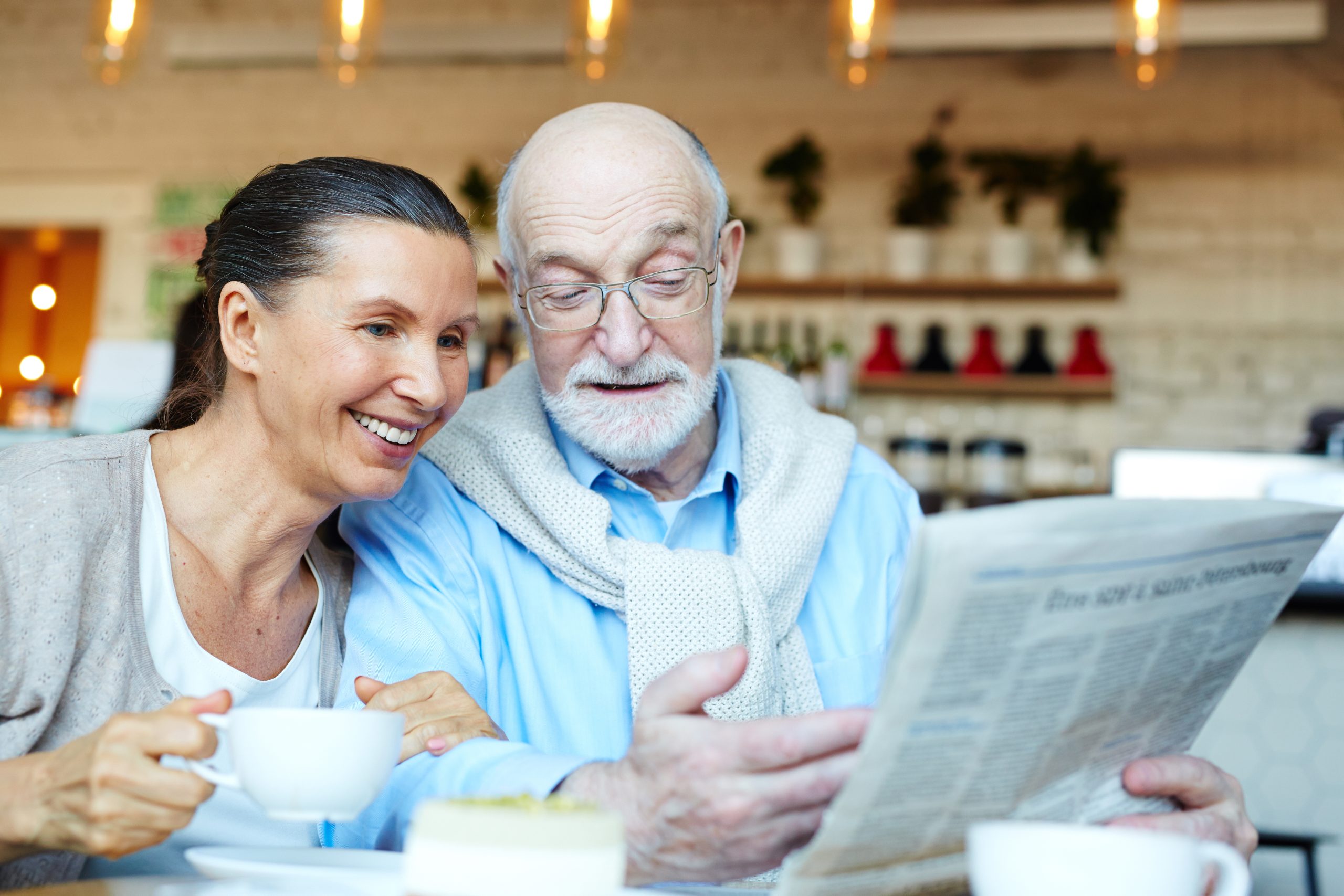 Mature man showing his wife latest news by cup of tea