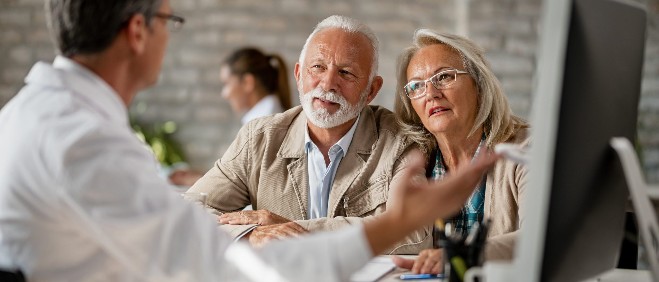 Senior couple talking with a doctor about their medical records while having consultations at clinic.