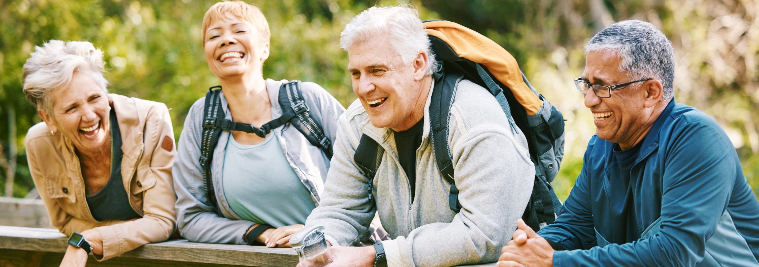 Finding Purpose in Retirement | Five Ways to Enjoy Retirement Elderly, people hiking and happy in park with fitness outdoor, relax on bridge while trekking in nature together. Health, wellness and hiker group, sport and active lifestyle motivation with cardio. 