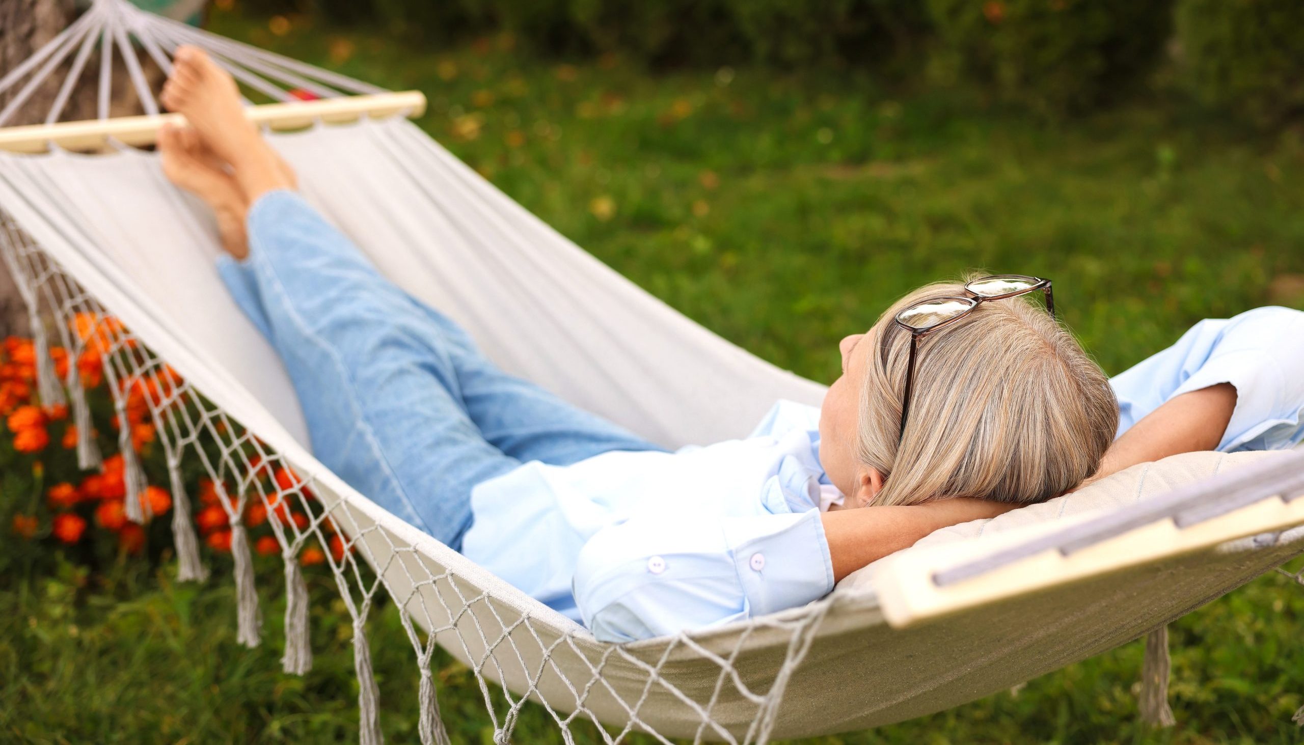 Senior woman resting in comfortable hammock outdoors mid-year retirement checkup
