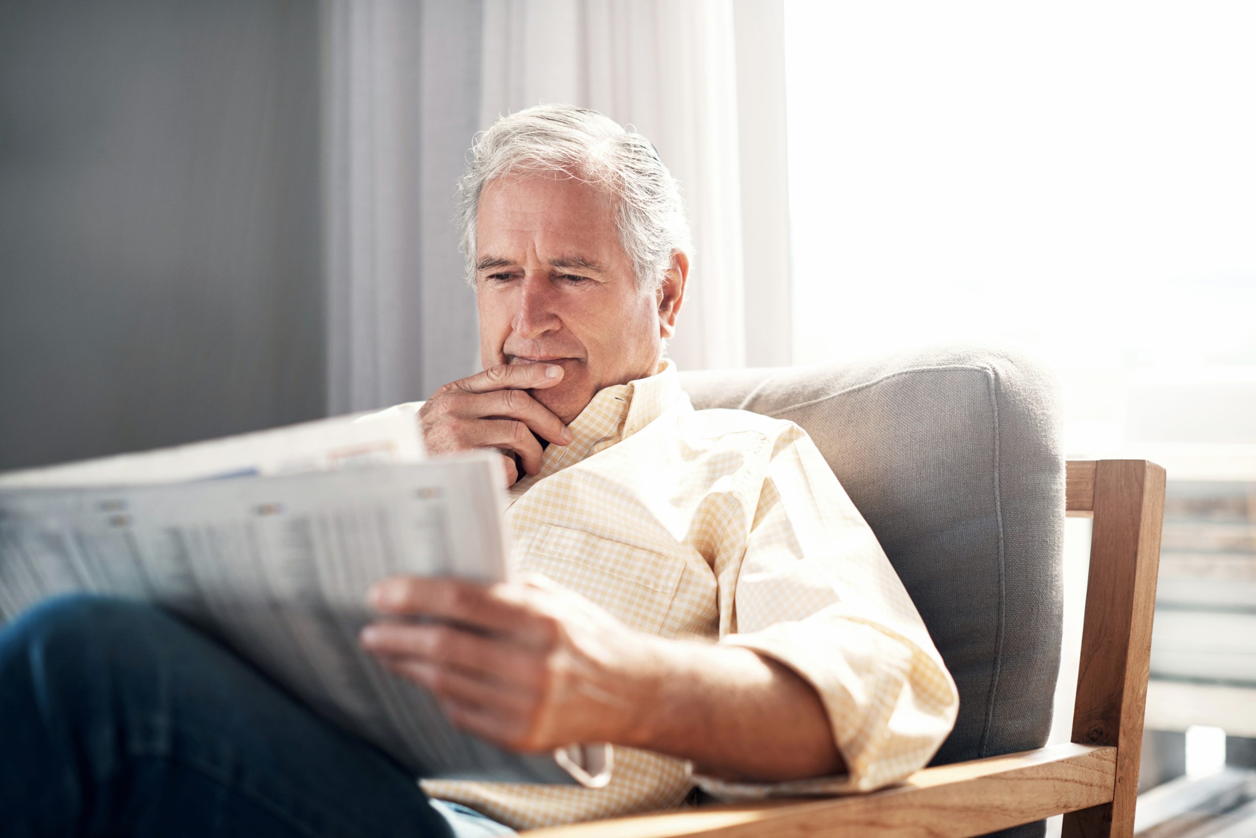 Shot of an elderly man reading a newspaper during a relaxing day at home A couple reviewing retirement planning documents one year after the One Big Beautiful Bill Act, discussing 2026 tax planning strategies with a financial advisor.